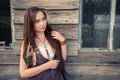 Beautiful country boho girl stands on the background of an old wooden house with windows