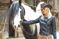 Beautiful country style blond woman with black and white horse Royalty Free Stock Photo