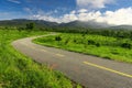 Beautiful countryside road in green field under blue sky Royalty Free Stock Photo