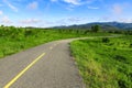 Beautiful countryside road in green field under blue sky Royalty Free Stock Photo