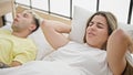 Beautiful couple covering ears for snore lying on bed at bedroom