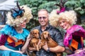 Beautiful couple of girls in vintage colourful clothes and wigs taking a photo with a man and his two dachshund dogs