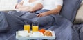 Beautiful couple having breakfast lying in bed at home. Handsome man and attractive woman are enjoying spending time Royalty Free Stock Photo