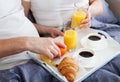 Beautiful couple having breakfast lying in bed at home. Handsome man and attractive woman are enjoying spending time Royalty Free Stock Photo