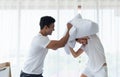 Beautiful couple having fun by fighting with a pillow on bed after waking up in bright bedroom Royalty Free Stock Photo
