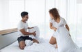 Beautiful couple having fun by fighting with a pillow on bed after waking up in bright bedroom Royalty Free Stock Photo