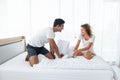 Beautiful couple having fun by fighting with a pillow on bed after waking up in bright bedroom Royalty Free Stock Photo