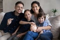 Beautiful couple and kids sit on sofa with piggy bank Royalty Free Stock Photo