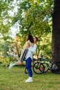 Beautiful couple kissing in the park on a background of bicycles and trees. The man raised his hands to the woman and kissed. Royalty Free Stock Photo