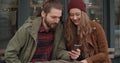 Beautiful couple looking at smartphone while sitting in outdoors restaurant. Royalty Free Stock Photo