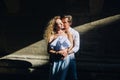 Beautiful couple in love gently hugging in sunlight in city street. stylish hipster groom and blonde bride embracing. romantic