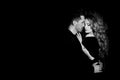 Beautiful couple in love hugging against black background. Studio black and white portrait photo of a girl blondes and a guy with Royalty Free Stock Photo