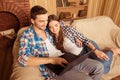 Beautiful couple in love sitting on the sofa with laptop and smiling Royalty Free Stock Photo