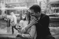 Beautiful couple. Loving guy hugs his charming girlfriend sitting on the windowsill in a cozy cafe. Black and white Royalty Free Stock Photo