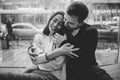 Beautiful couple. Loving guy hugs his charming girlfriend sitting on the windowsill in a cozy cafe. Black and white Royalty Free Stock Photo