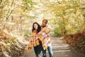 Beautiful couple man woman in love. Boyfriend and girlfriend wrapped in yellow blanket plaid hugging in a park on autumn fall day