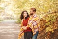 Beautiful couple man woman in love. Boyfriend and girlfriend wrapped in yellow blanket plaid hugging in a park on autumn fall day