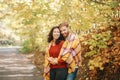 Beautiful couple man woman in love. Boyfriend and girlfriend wrapped in yellow blanket plaid hugging together in a park on autumn