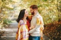 Beautiful couple man woman in love. Smiling boyfriend and girlfriend wrapped in yellow blanket hugging in park on autumn fall day