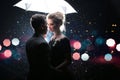 Beautiful couple man with woman with white umbrella in flash lights and rain drops