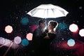 Beautiful couple man with woman with white umbrella in flash lights and rain drops