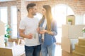 Beautiful couple moving to a new house, smiling cheerful drinking a cup of coffee