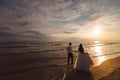 A beautiful couple of newlyweds, the bride and groom walking on the beach. Gorgeous sunset and sky. Wedding dresses, a Royalty Free Stock Photo