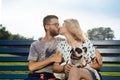 Beautiful couple sitting with French bulldog on bench in park. Royalty Free Stock Photo