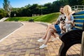 Beautiful couple sitting with French bulldog on bench in park. Royalty Free Stock Photo