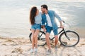 beautiful couple sitting together on bicycle on beach