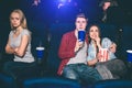 Beautiful couple is sitting together and watching movie. Brunette girl is eating popcorn and guy is drinking coke. She Royalty Free Stock Photo