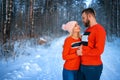 Beautiful couple standing arm in arm in the red sweater in the background of the forest in winter , a walk in the winter woods