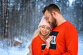 Beautiful couple standing arm in arm in the red sweater in the background of the forest in winter , a walk in the winter woods