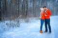 Beautiful couple standing arm in arm in the red sweater in the background of the forest in winter , a walk in the winter woods