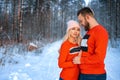 Beautiful couple standing arm in arm in the red sweater in the background of the forest in winter , a walk in the winter woods Royalty Free Stock Photo