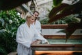 Beautiful couple standing by hot tub, wearing bathrobes, enjoying romantic wellness weekend in spa. Concept of