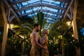 Beautiful couple standing in hotel greenhouse, looking at each another, enjoying romantic wellness weekend in spa