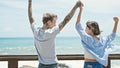 Beautiful couple standing together with hands raised up at seaside Royalty Free Stock Photo