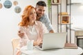 Young man and ginger woman have fun shopping online together on computer. Royalty Free Stock Photo
