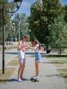 An attractive smiling fellow teaching a girl riding on a longboard in a park on a natural blurred background. Royalty Free Stock Photo