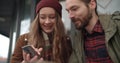 Beautiful couple looking at smartphone while sitting in outdoors restaurant. Royalty Free Stock Photo