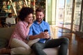 Beautiful  couple using a smartphone and smiling while sitting on sofa Royalty Free Stock Photo