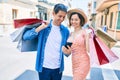 Beautiful couple on vacation smiling happy holding shopping bags using smartphone at street of city Royalty Free Stock Photo