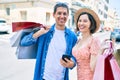 Beautiful couple on vacation smiling happy holding shopping bags using smartphone at street of city Royalty Free Stock Photo