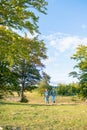 Beautiful couple walking with backpacks on the green meadow, while traveling high in the mountains during the summer