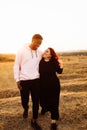 Beautiful couple walking at the field, attractive husband gently hug adorable wife, overjoyed woman smiling, happy