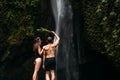 Beautiful couple at a waterfall in Indonesia, rear view. Man and woman at the waterfall. Royalty Free Stock Photo