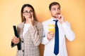 Beautiful couple wearing business clothes drinking take away coffee holding folder serious face thinking about question with hand