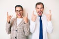 Beautiful couple wearing business clothes shouting with crazy expression doing rock symbol with hands up Royalty Free Stock Photo