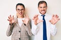 Beautiful couple wearing business clothes smiling funny doing claw gesture as cat, aggressive and sexy expression Royalty Free Stock Photo